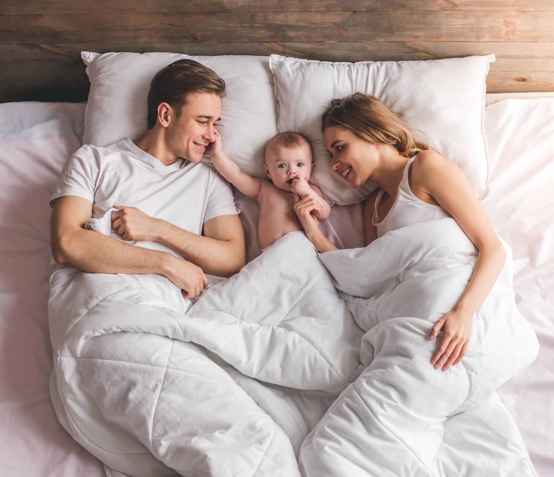 des parents heureux avec bébé dans leur lit