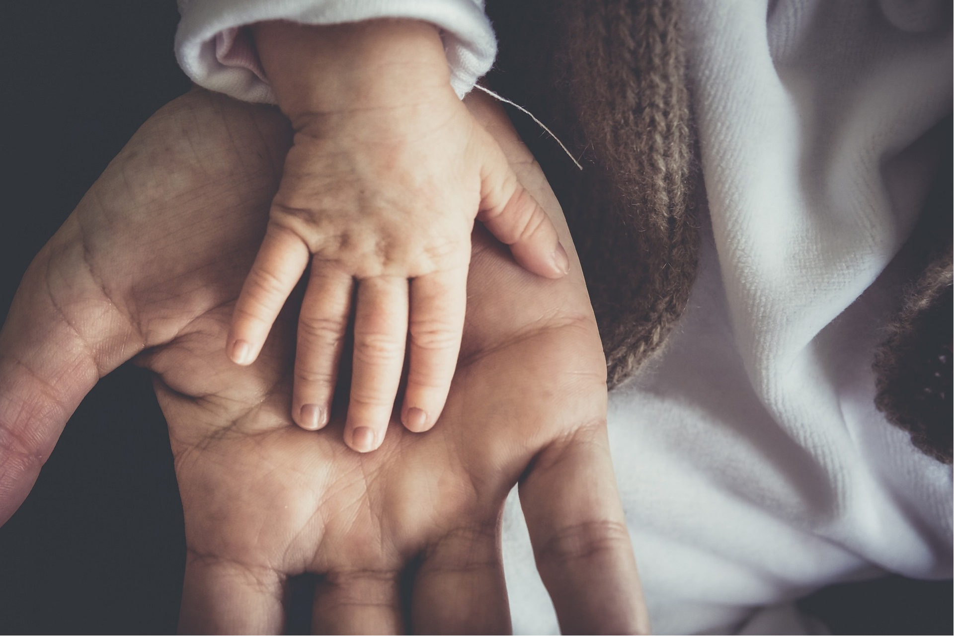 Une main de bébé posée sur une main d'un homme