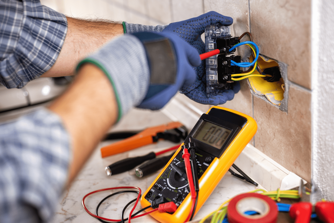 Homme entrain de bricoler une prise électrique illustrant le service d'électricité générale