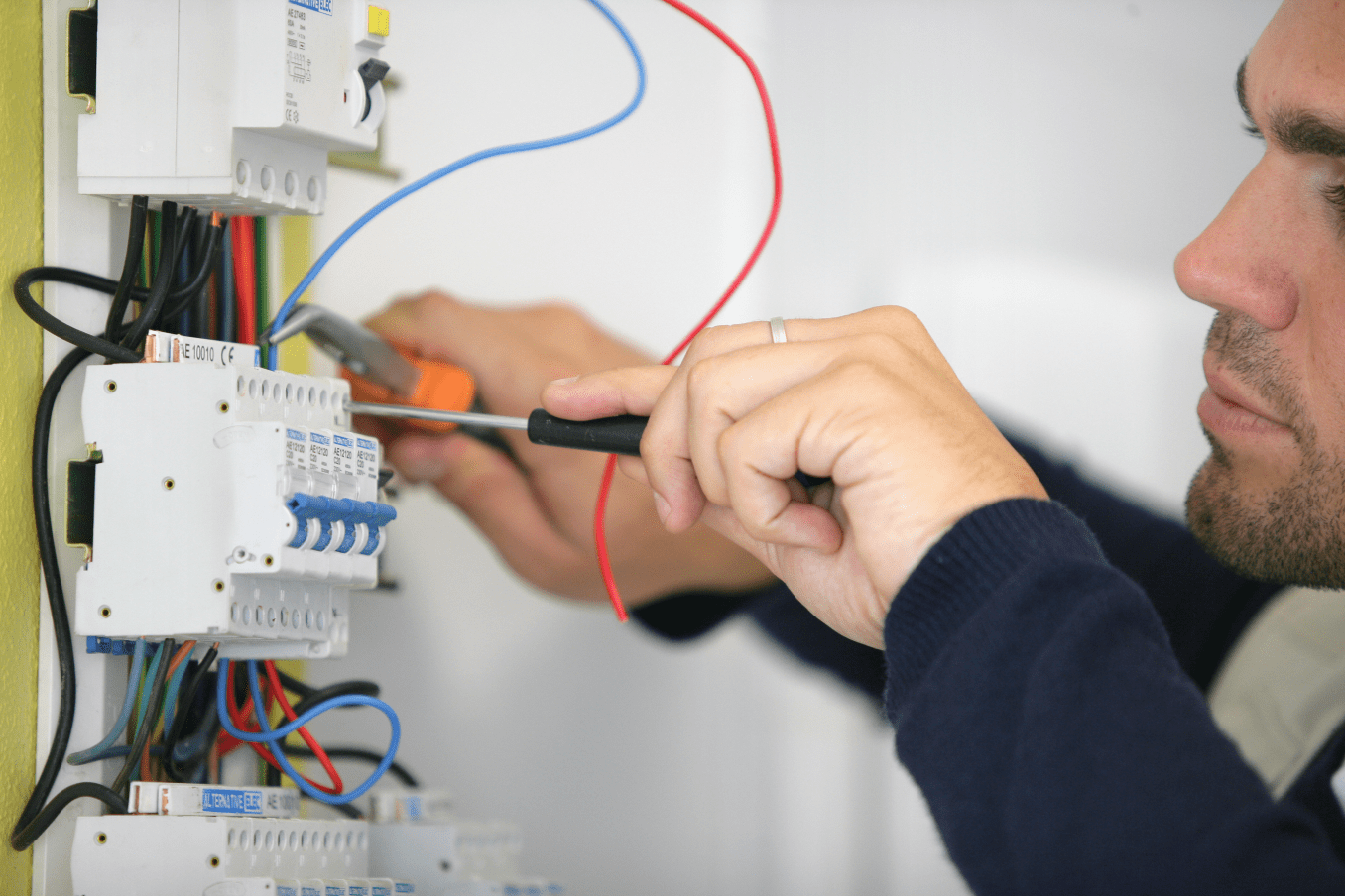 Homme entrain de bricoler une prise électrique illustrant le service d'électricité générale chez kozy services